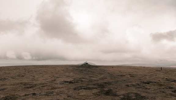 A cairn on the summit of a bare hill top.